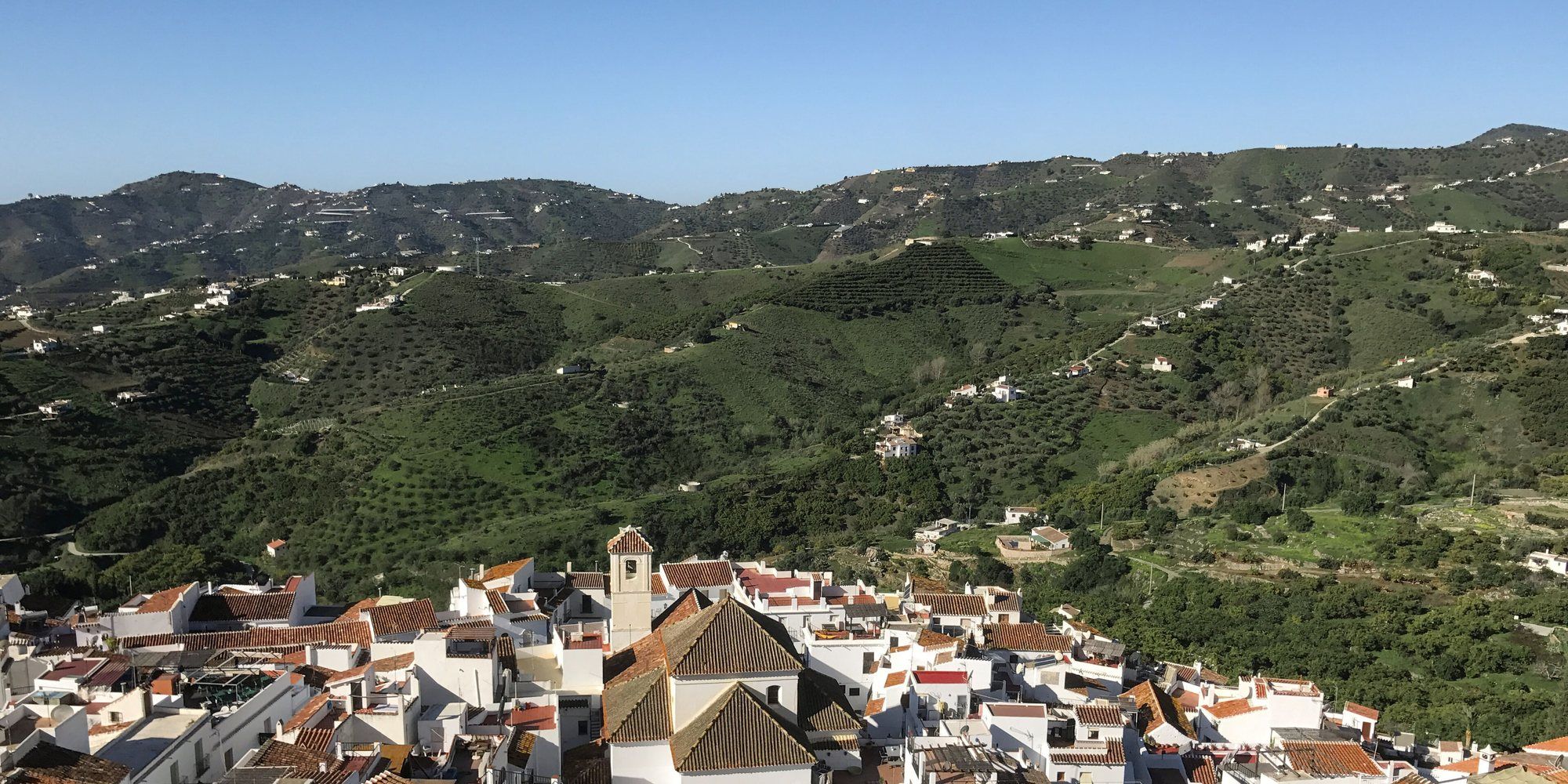 Frigiliana, a white village in the province of Málaga: whitewashed houses with tiled roofs below green hills.