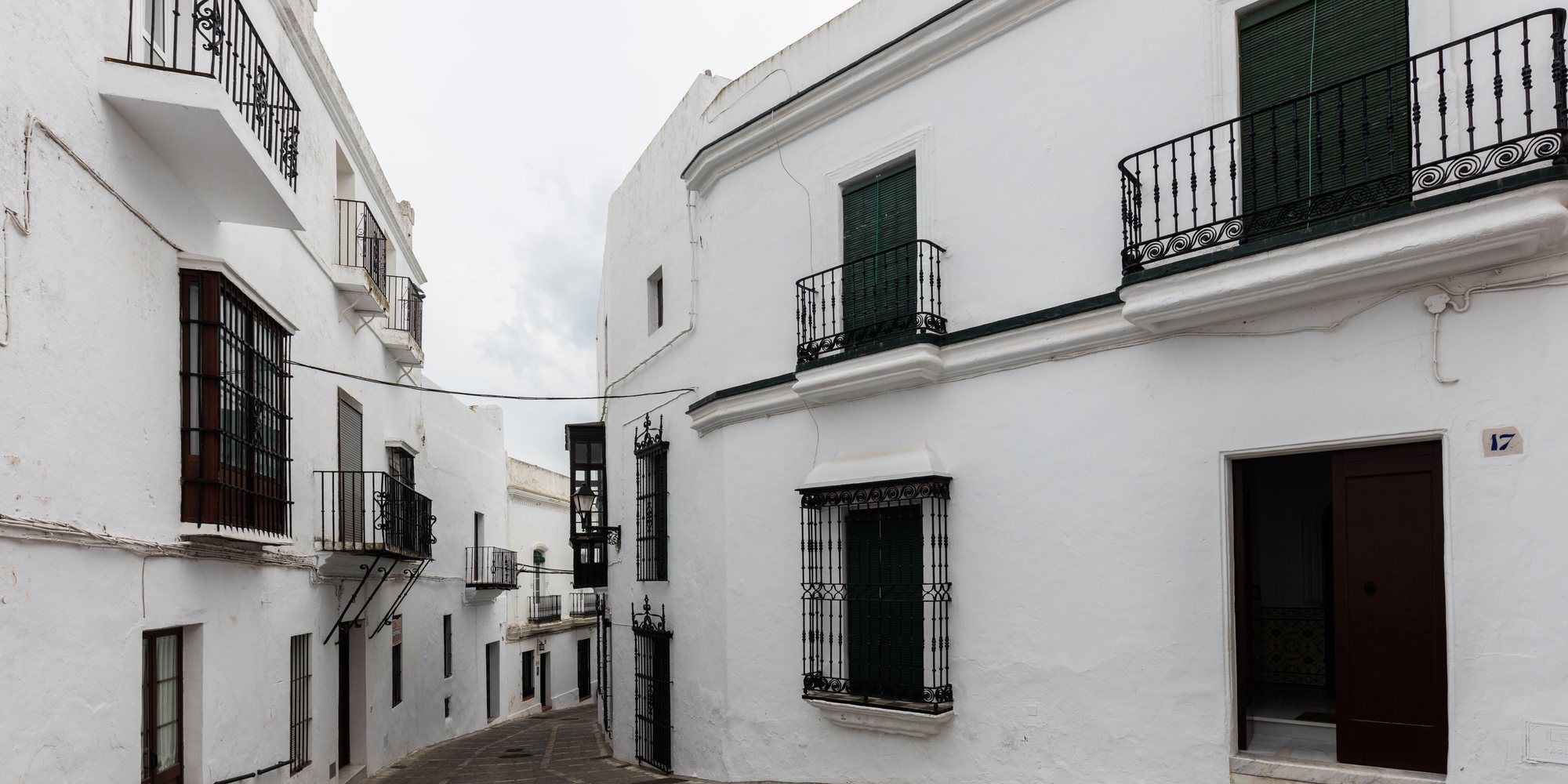 A street of whitewashed houses with wrought-iron balconies and green shutters in Vejer de la Frontera, in the province of Cádiz.
